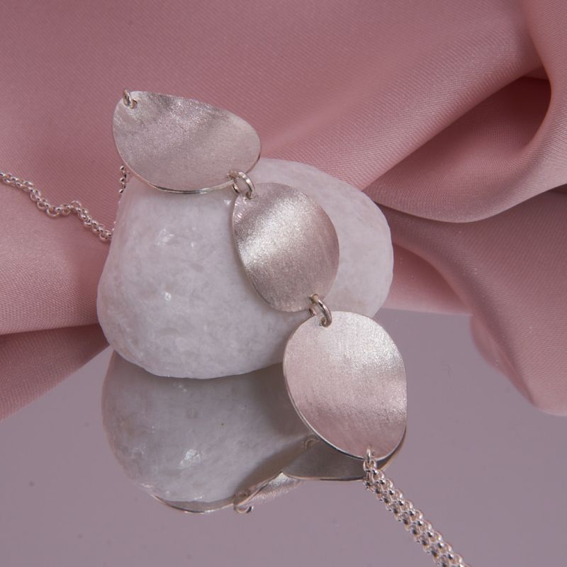 Detailaufnahme der diamantierten und polierten Silberplättchen des Isola Colliers mit Fokus auf die beweglichen Ösen.